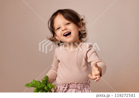 smiling very excited child girl holding fresh green salad on beige background. healthy baby food. 119272581