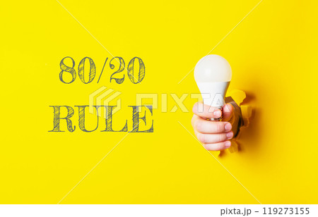 A person holding a light bulb with the words 80 20 rule written below them 119273155