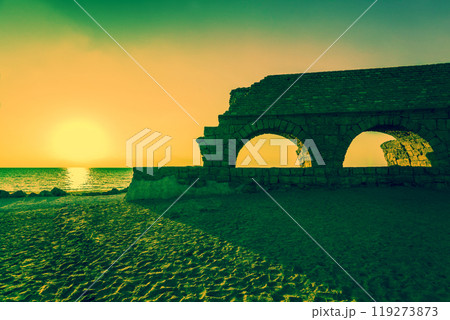 Remains of the ancient Roman aqueduct in ancient city Caesarea at sunset. Israel. 119273873