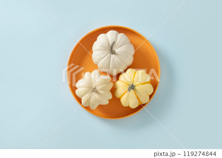 Autumn concept with three pumpkins in seasonal orange plate on blue background. View from above. Thanksgiving Day sale concept. Autumn concept with three pumpkins in seasonal orange plate on blue background. View from above. Thanksgiving Day sale concept. 119274844