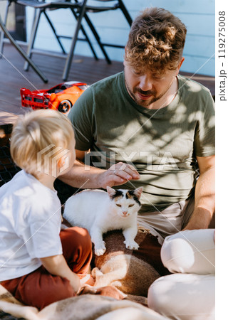 Father and son bonding outdoors with their cat on a sunny day. Memories and enjoying family time Father and son bonding outdoors with their cat on a sunny day. Memories and enjoying family time 119275008