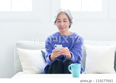 リビングでスマートフォンを使う中高年の女性 119277681