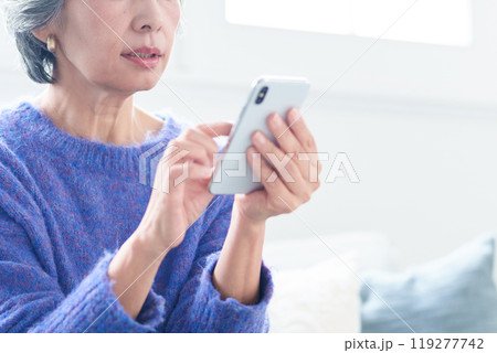 リビングでスマートフォンを使う中高年の女性 119277742