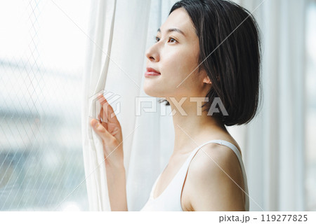朝窓際でカーテンを開ける女性 119277825