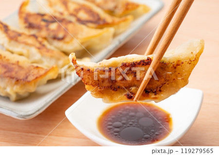 タレにつけて食べる美味しそうな焼き餃子のクローズアップ タレにつけて食べる美味しそうな焼き餃子のクローズアップ 119279565