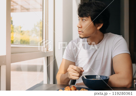 Happy man is having breakfast in the hotel dinning room. 119280361