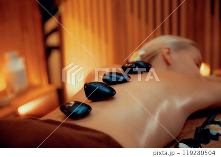 Hot stone massage at spa salon in luxury resort with warm candle light.Quiescent Hot stone massage at spa salon in luxury resort with warm candle light.Quiescent 119280504