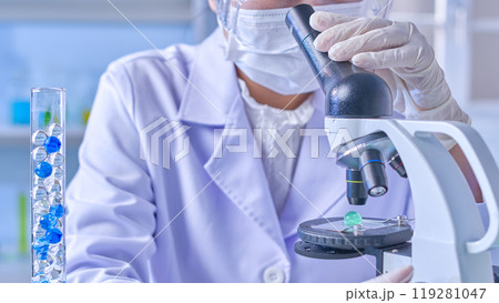 Close up front view shot at a female scientist scientist is using microscope to observe a blue gel ball. Copy space for adding text and elements of design Close up front view shot at a female scientist scientist is using microscope to observe a blue gel ball. Copy space for adding text and elements of design 119281047