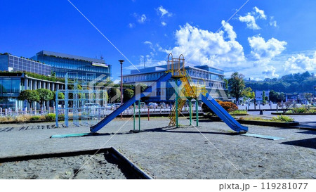 公園の砂場とすべり台とジャングルジム、背景に建物と青空と雲 公園の砂場とすべり台とジャングルジム、背景に建物と青空と雲 119281077