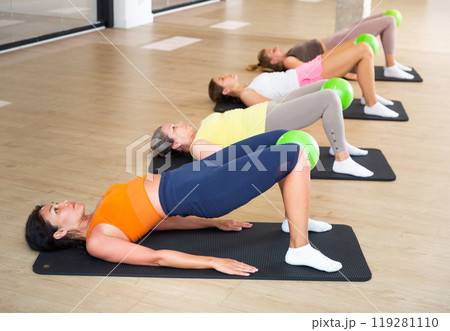 Women doing hip bridge with pilates ball 119281110