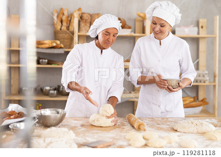 Two women bakers making dough in workshop 119281118