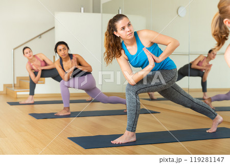 Girl doing twisting asana Parivritta Parsvakonasana in yoga studio Girl doing twisting asana Parivritta Parsvakonasana in yoga studio 119281147