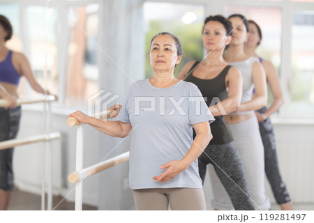 Senior woman practicing battement tendu in beginner ballet class Senior woman practicing battement tendu in beginner ballet class 119281497