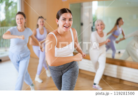 Group of happy young mature sports women in activewear exercising dynamic dancing movemens in modern gym studio Group of happy young mature sports women in activewear exercising dynamic dancing movemens in modern gym studio 119281500