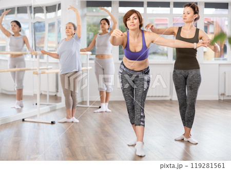 Female ballet trainer adjusting poses of middle aged woman in amateur class 119281561