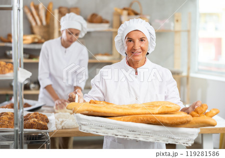 Elderly woman baker with basket of baguettes Elderly woman baker with basket of baguettes 119281586
