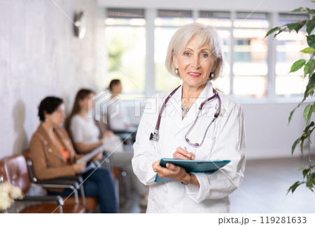 Portrait of mature female doctor wearing uniform and stethoscope with folder 119281633
