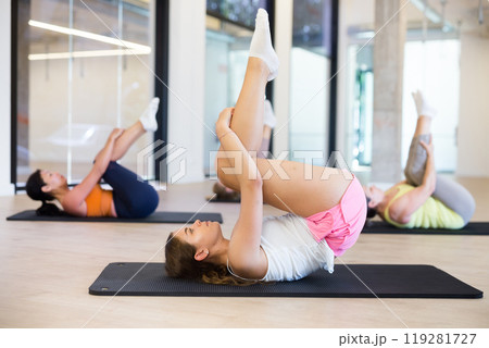 Group of women doing rolling back stretch Group of women doing rolling back stretch 119281727