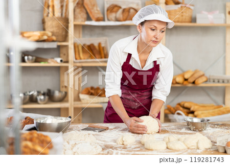 Professional female baker kneading dough in artisan bakery Professional female baker kneading dough in artisan bakery 119281743