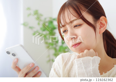 スマホを見て冴えない表情をする女性 119282362