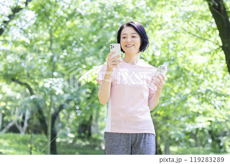 トレーニング スマホを見ているミドル女性 トレーニング スマホを見ているミドル女性 119283289