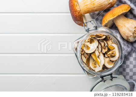 Dried porcini mushrooms. Sliced boletus in jar on white table. Top view. Dried porcini mushrooms. Sliced boletus in jar on white table. Top view. 119283418