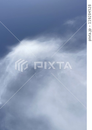A close-up view of a dense, white cloud against a blue sky 119284528