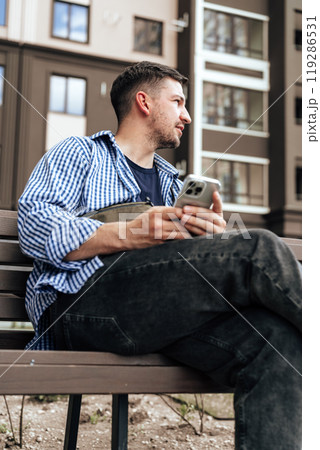 Young man sitting on a bench in a park 119286531