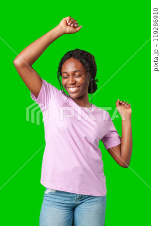 A young woman with braids expresses excitement with a clenched fist against a bright green background 119286910