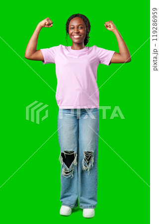 A young woman with braids expresses excitement with a clenched fist against a bright green background A young woman with braids expresses excitement with a clenched fist against a bright green background 119286959