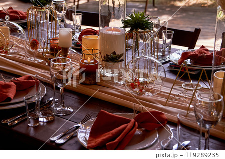 Table setting with orange napkins and glasses. Classic. Warm shades. 119289235