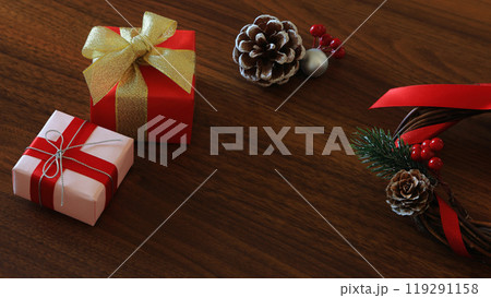 赤とゴールドリボンのクリスマスギフトのボックスとリースと松ぼっくり:オーク木目背景 赤とゴールドリボンのクリスマスギフトのボックスとリースと松ぼっくり:オーク木目背景 119291158