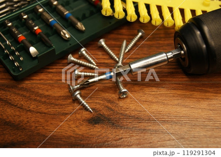 Dowels, screws, screwdriver, bit set. Tools and fasteners on a wooden surface 119291304