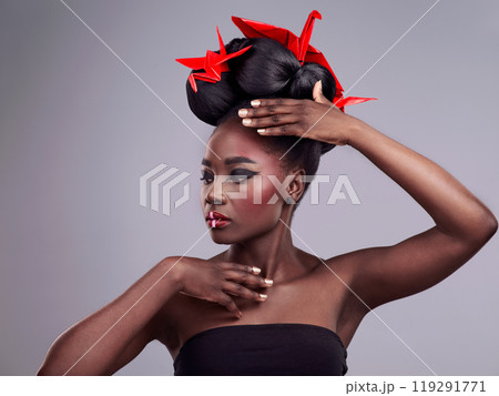 Woman, beauty and origami in studio for creative makeup with red, Asian culture and paper bird. African model, bold cosmetics and grey background for art deco with confidence and Japanese design 119291771