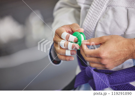 Brazilian jiu jitsu, hands and person with tape in gym for training, fitness or professional fighting sport. Injury, protection and martial arts athlete with gi, safety for fingers or workout in dojo Brazilian jiu jitsu, hands and person with tape in gym for training, fitness or professional fighting sport. Injury, protection and martial arts athlete with gi, safety for fingers or workout in dojo 119291890