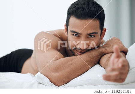 Happy, man and hand for welcome to bed in morning with blankets and pillows for romance or intimacy at home. Asian male person and model with smile, confidence and sexy greeting or gesture in bedroom 119292195