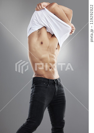 Man, healthy and muscle in studio for undressing with confidence, exercise or strong with stomach. Male person, gray background and shirtless with jeans for fitness, motivation for workout or sport 119292822