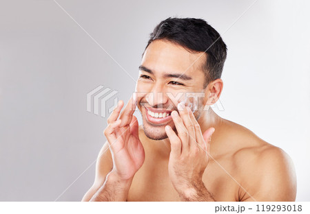 Happy Asian man, face or cream for beauty in studio with smile, natural cosmetics or glow for shine. Dermatology, antiaging product or male model applying skincare lotion or creme on white background 119293018