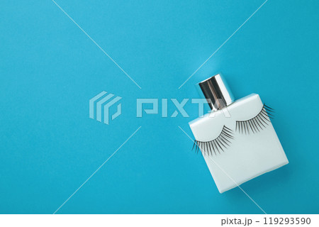 Perfume bottle with eyelashes on blue background Perfume bottle with eyelashes on blue background 119293590