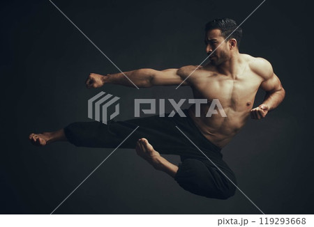 Martial arts, kick and man in jump, motion and fitness for wellbeing in studio backdrop for karate or capoeira. Male person, foot and taekwondo in black background for sports, wellness or workout 119293668