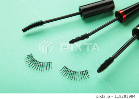 Close up of black eyeliners and mascara brush on mint background 119293994