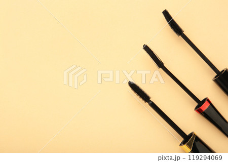 Various mascara wands on beige background with copy space 119294069