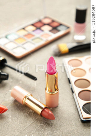 Makeup lipstick and cosmetics on grey background. Flat lay, top view. Beauty and fashion concept. Makeup lipstick and cosmetics on grey background. Flat lay, top view. Beauty and fashion concept. 119294097