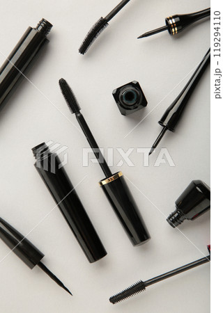 Close up of black eyeliners and mascara brush on grey background. Vertical photo. Close up of black eyeliners and mascara brush on grey background. Vertical photo. 119294110