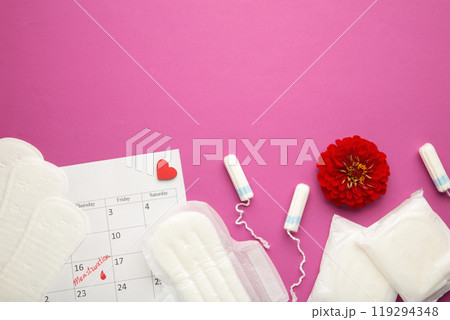 Menstruation calendar with cotton tampons and pads with flower on pink background. Woman critical days, woman hygiene protection. Menstrual pain Menstruation calendar with cotton tampons and pads with flower on pink background. Woman critical days, woman hygiene protection. Menstrual pain 119294348