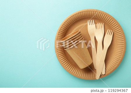Eco craft paper tableware. Paper cups, dishes, bag, fast food containers and wooden cutlery on blue background. Zero waste. Recycling concept. Copy space 119294367