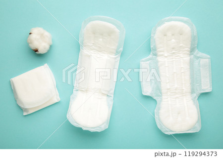 White sanitary pad, hygiene protection on a mint background. Gynecological menstrual cycle. A rose flower lies on a menstrual pad. First menstruation 119294373