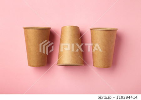 Disposable paper cups on pink background. Coffee concept. Disposable paper cups on pink background. Coffee concept. 119294414
