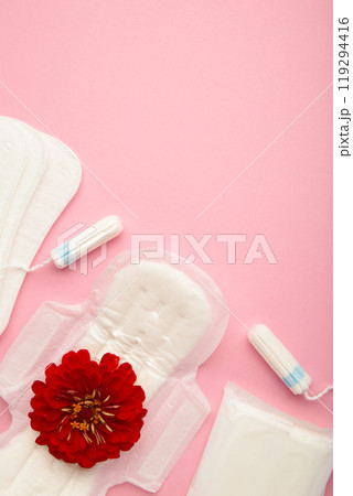 Menstrual tampons and pads on a pink background. Menstruation cycle. Hygiene and protection. A rose flower lies on a menstrual pad. 119294416