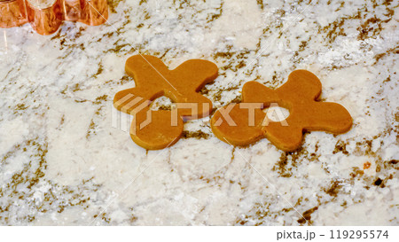 Using various festive cookie cutters, we're cutting out charming gingerbread cookies from the rolled dough on the sleek marble counter, bringing holiday cheer to the modern kitchen. Using various festive cookie cutters, we're cutting out charming gingerbread cookies from the rolled dough on the sleek marble counter, bringing holiday cheer to the modern kitchen. 119295574